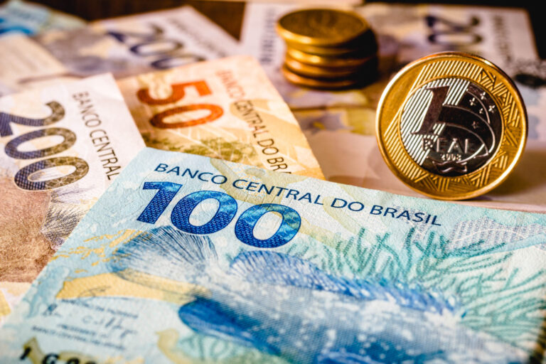 Close-up da moeda brasileira, com cédulas coloridas de 100, 50 e 200 reais e moedas de um real empilhadas. Os desenhos vibrantes destacam imagens da vida selvagem - perfeitas para as loterias caixa: r 135,39 milhões em prêmios aguardam o próximo ganhador.