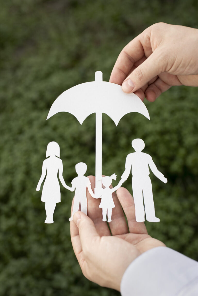 Duas mãos seguram um recorte de papel de uma família de quatro pessoas sob um guarda-chuva, simbolizando proteção, com um fundo verde desfocado - exatamente como o software para lotéricas protege suas operações comerciais.