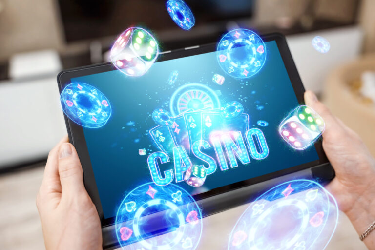 Uma pessoa segura um tablet que exibe uma tela de cassino virtual com fichas de pôquer, dados e cartas brilhantes flutuando ao redor do dispositivo, sugerindo uma experiência de jogo on-line enquanto deputados defendem a liberação dos cassinos no Brasil.
