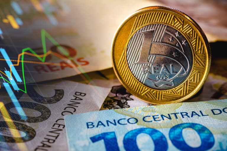 Um close-up de uma moeda de 1 real brasileira em cima de cédulas de 100 e 200 reais, com um gráfico financeiro sobreposto ao fundo, destacando o impacto das loterias de novos valores.