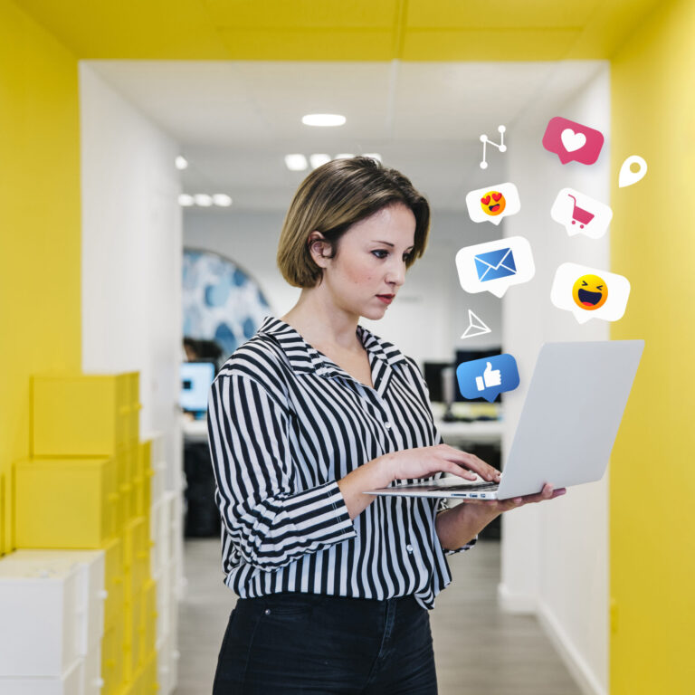 Uma mulher de camisa listrada está em um corredor de escritório amarelo, usando um laptop. Ícones coloridos de mídia social flutuam acima do computador, mostrando como o instagram para lotéricas pode aumentar o engajamento com corações, curtidas e mensagens.