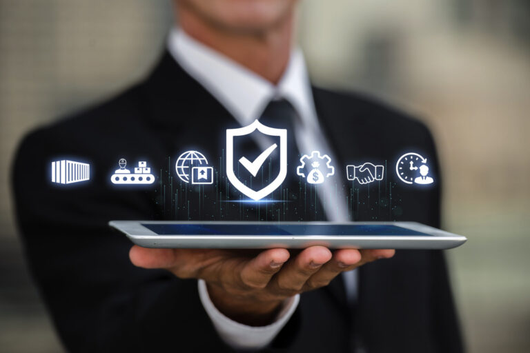 Uma pessoa de terno segura um tablet com ícones digitais flutuantes acima dele, incluindo um escudo com uma marca de verificação, representando a segurança cibernética, conceitos de tecnologia e 8 dicas para criar um sistema eficiente e seguro.