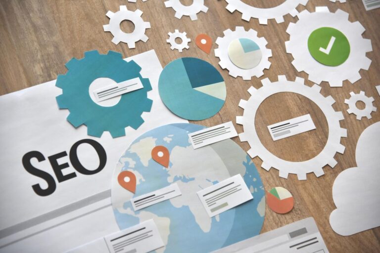 Recortes de papel de engrenagens, um globo terrestre com marcadores de localização, gráficos e marcas de verificação dispostos em uma superfície de madeira, ao lado de um documento rotulado como SEO, simbolizando software para lotéricas em otimização de mecanismos de busca e análise de dados.
